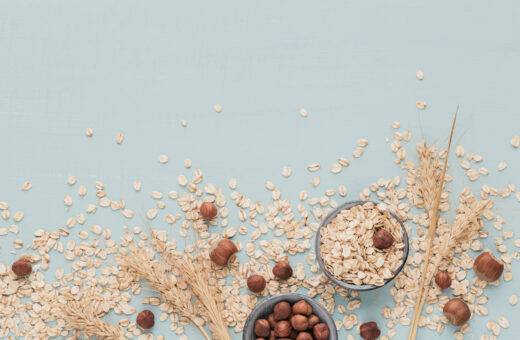 Intensive Oat lotion, Dry oatmeal flakes with ears of wheat and hazelnuts on light green background. Wheat seeds background.