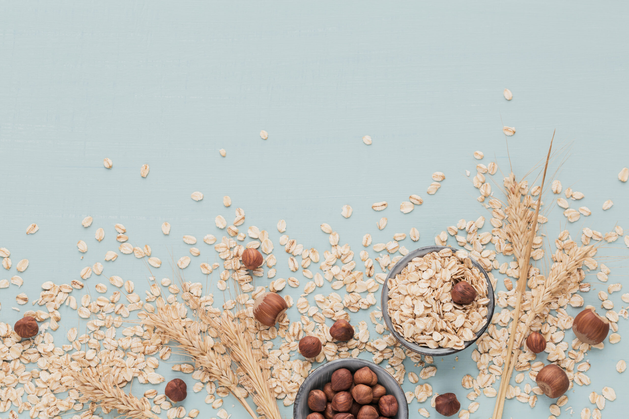 Intensive Oat lotion, Dry oatmeal flakes with ears of wheat and hazelnuts on light green background. Wheat seeds background.
